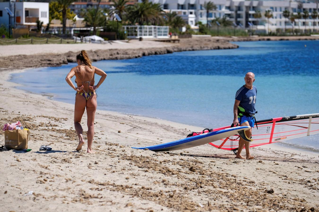 Baños de sol y windsurf en Ibiza. A pesar de que hasta la fase 3 no estará permitido el baño son muchas las personas que aprovechan para dar paseos, tomar el sol y hacer deporte, como ya hicieran la semana pasada las islas que fueron la avanzadilla. Sobre estas líneas, la playa de Talamanca de Ibiza hoy