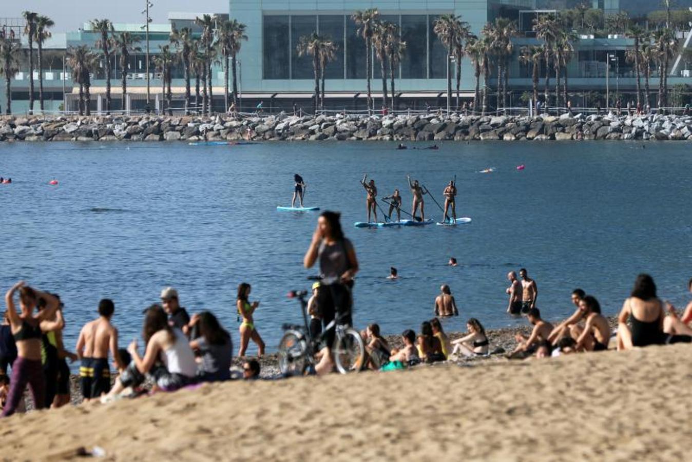 Gente practicando 'paddle boarding' en la playa de la Barceloneta. 