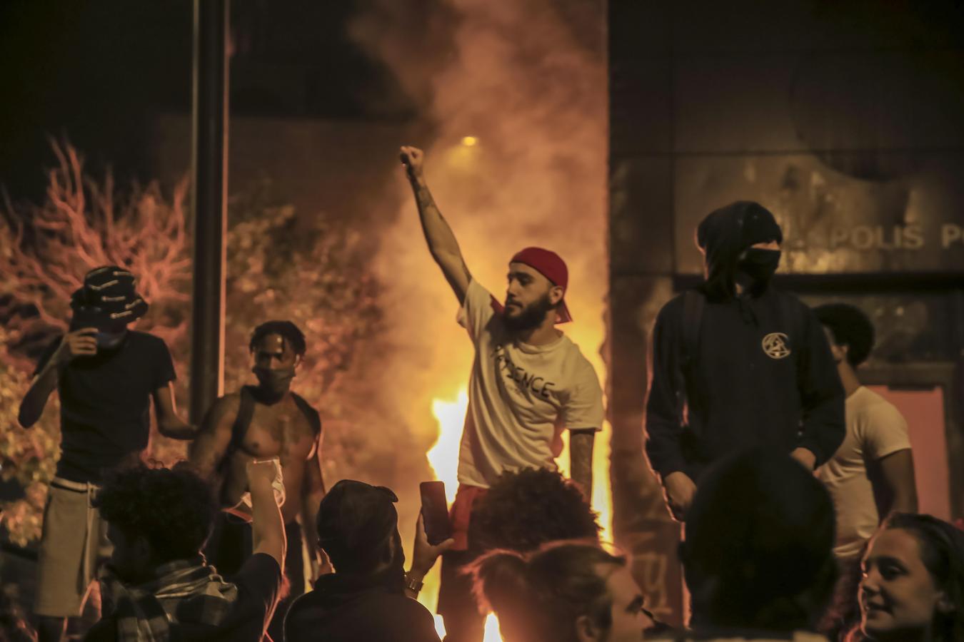 Disturbios en Mineápolis. Varios manifestantes protestan con el brazo en alto tras los incendios en Mineápolis