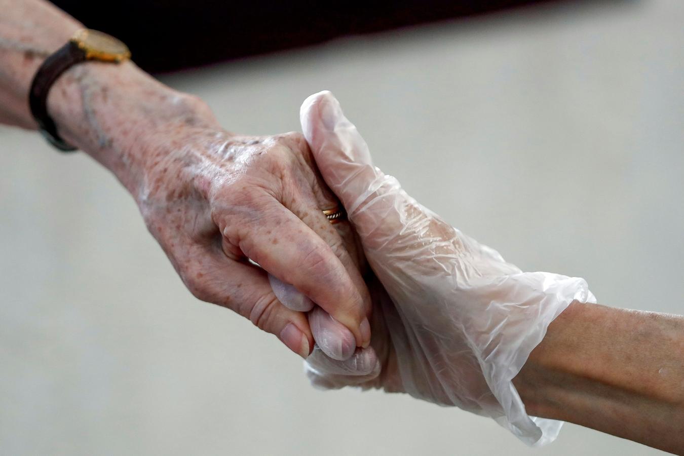 Manos estrechadas con guantes. Aunque está prohibido, una mujer no ha podido evitar estrechar la mano de su madre, provista de guantes, en la visita al geriátrico en donde está ingresada en Madrid. Hay que mantener dos metros de distancia y solo puede acudir una persona a ver al mayor