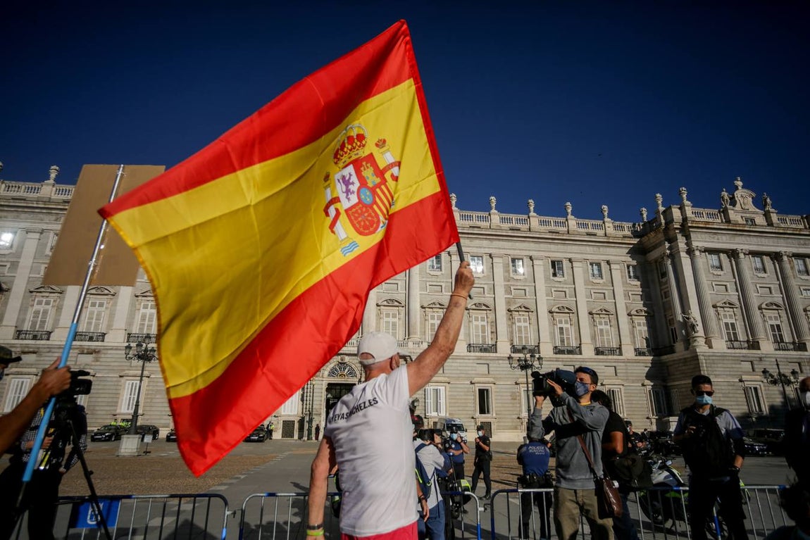 Un hombre ondea una bandera de España en el exterior del Palacio Real antes del inicio de la ceremonia de Estado. 
