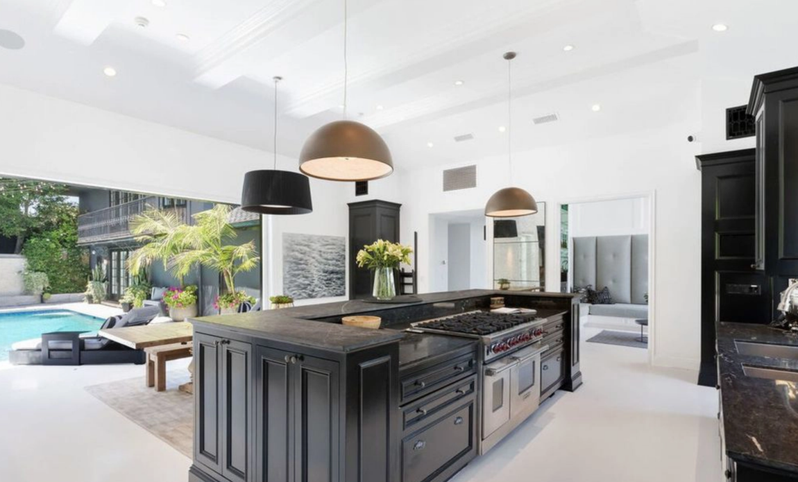 Así es la propiedad que vende Calvin Harris. La cocina destaca por sus muebles oscuros y sus electrodomésticos de alta gama. Dispone de una isla con barra de desayuno y espacio de almacenaje, así como de una mesa de madera en la que almorzar o cenar. Este espacio dispone de salida directa a la piscina.