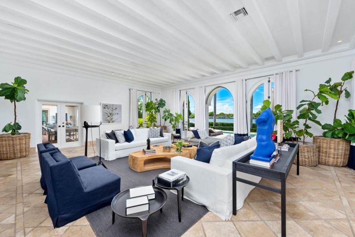 La espectacular mansión de Cher en Miami. El salón principal comunica con el jardín y posee una clara influencia marina en el mobiliario y detalles como por ejemplo los cojines azules. En él se aúna mobiliario tanto de madera como hierro y mimbre que le confieren un aire cálido y elegante.