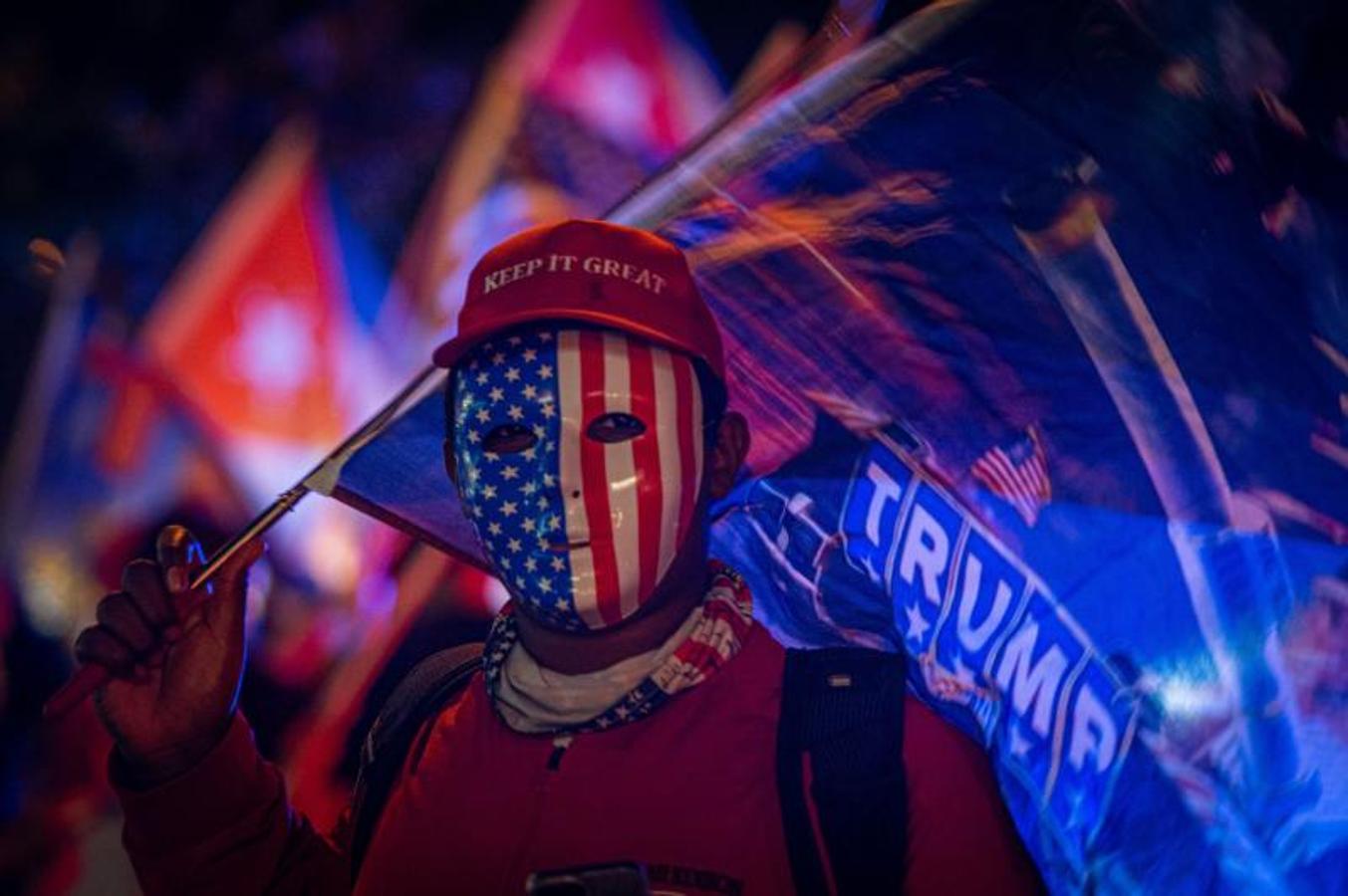 Un simpatizante de Donald Trump viste una careta con la bandera estadounidense en el icónico café Versailles de la Calle Ocho en Miami, Florida. 