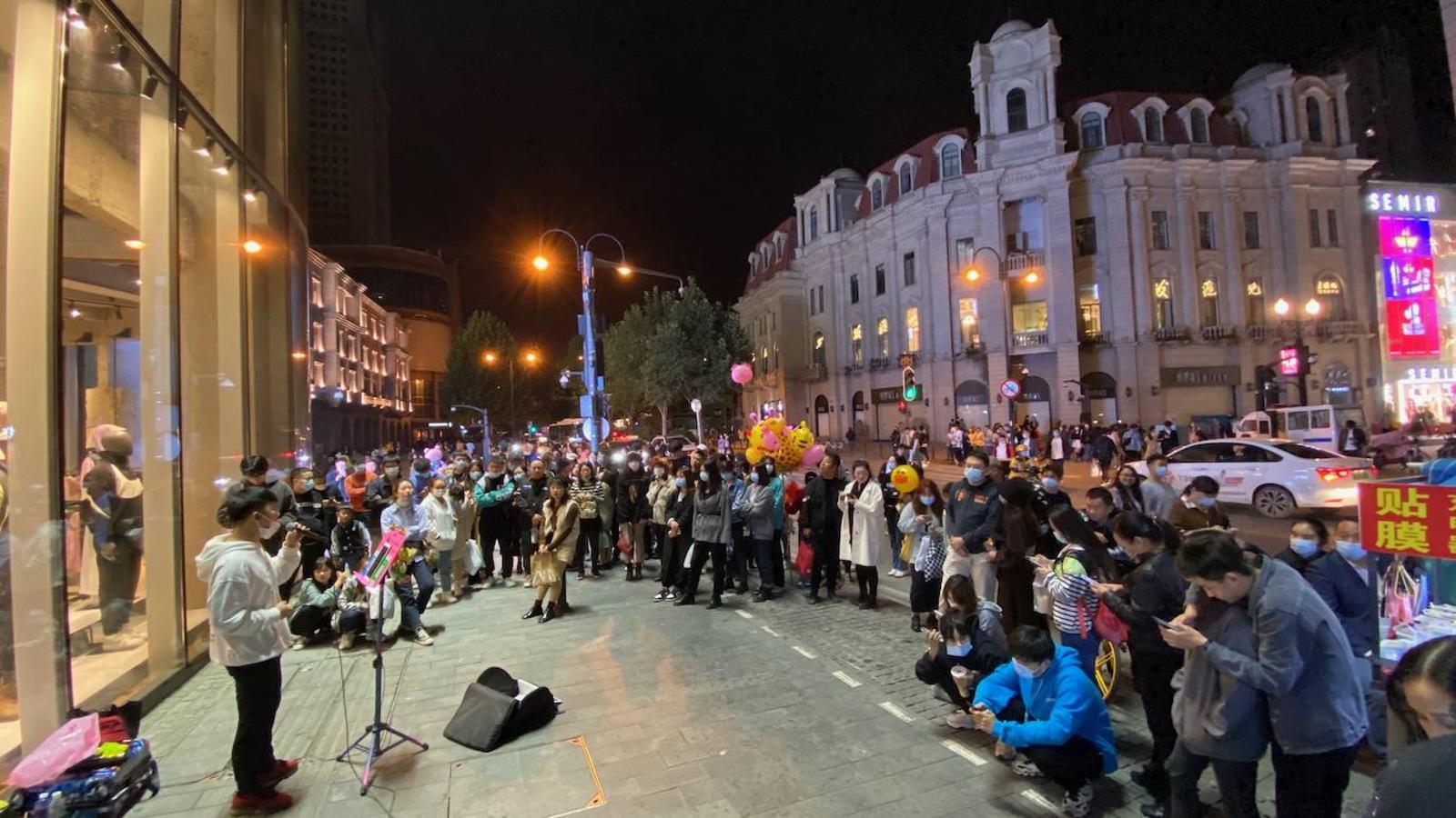 Aunque la mayoría suele llevar mascarilla en Wuhan y el resto de China, ya se ve a bastante gente sin ella en los espacios abiertos, como entre el público de este músico callejero. 