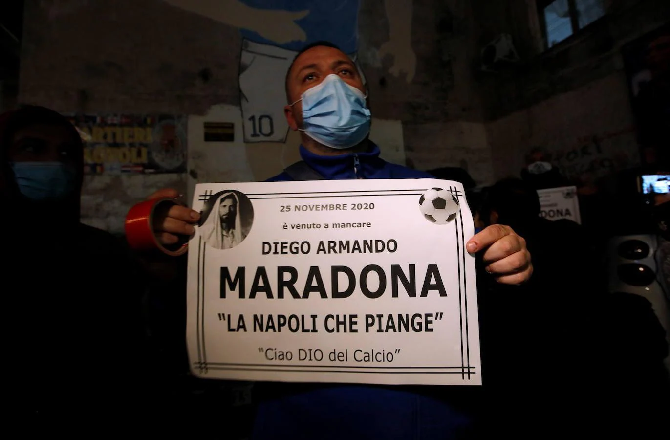 Un aficionado del Nápoles muestra un cartel en el que se lee: «La Nápoles que llora. Adiós dios del fútbol». 
