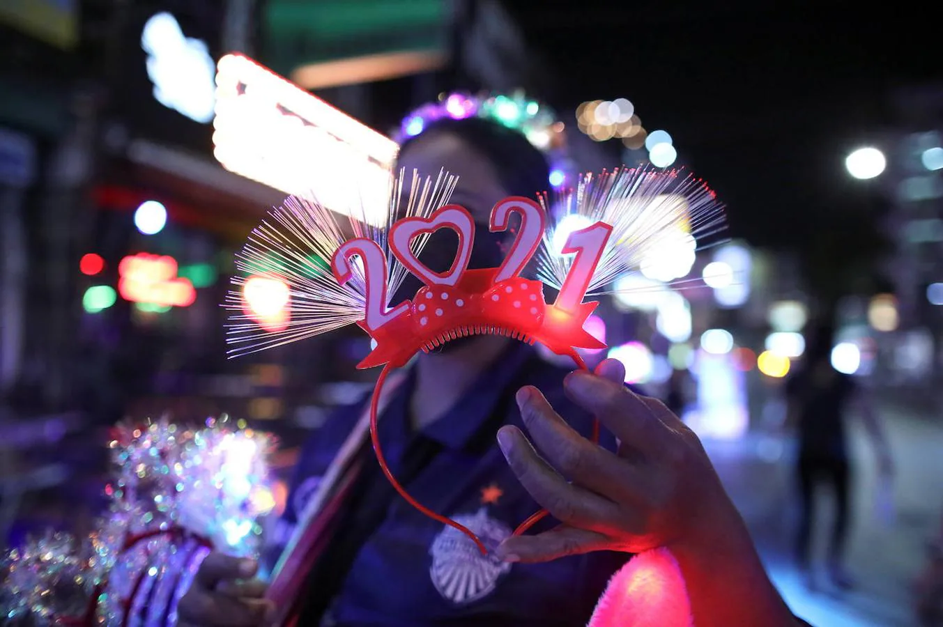 Una vendedora ambulante muestra una diadema especial para celebrar la llegada del 2021 en Bangkok (Tailandia) horas antes de que comience el Año Nuevo en el país.. 