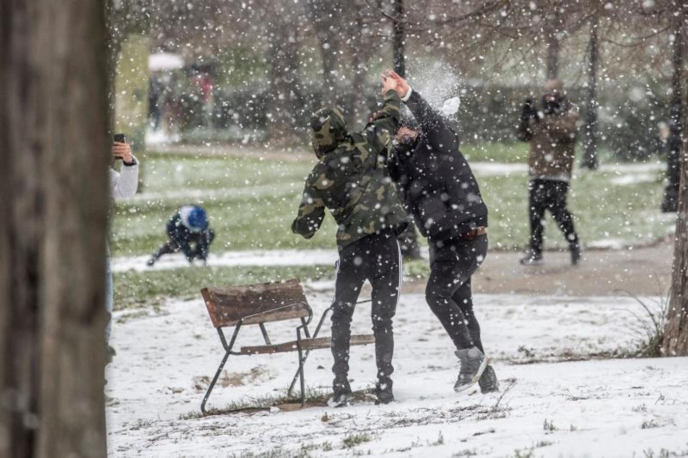 Dos jóvenes juegan con la nieve caída esta mañana en Madrid al filo del mediodía. 