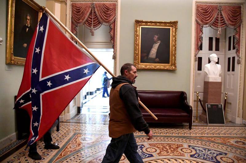 Asalto al capitolio. Un partidario del presidente Donald Trump lleva una bandera confederada en el Capitolio