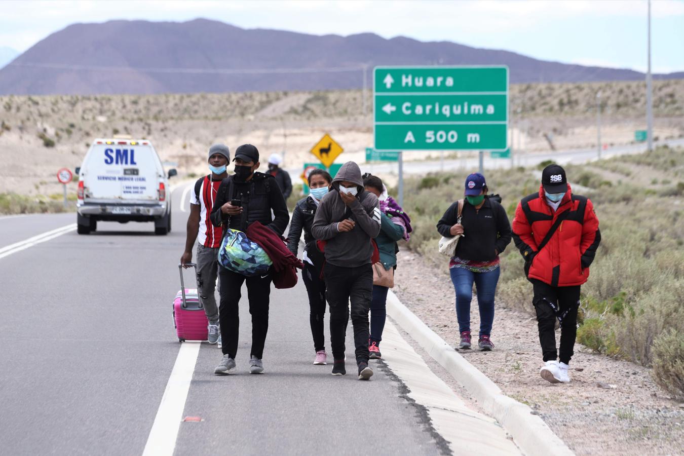 Un grupo de venezolanos caminan por el arcén de una carretera. 