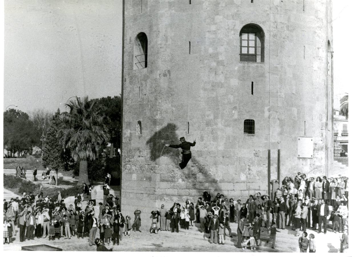 En esta imagen, de 1982, se puede apreciar como un bombero ofrece una exhibición de sus técnicas de rescate a un atento grupo de sevillanos, con la Torre del Oro como escenario