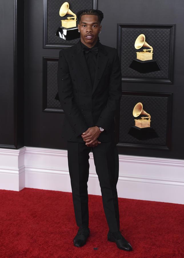 Lil Baby - Alfombra roja de los Grammy 2021. Hizo del negro su elección con un traje de corte slim fit al que añadió una camisa negra y una pajarita del mismo tono. Remató su elección con un elegante Patek Philippe.