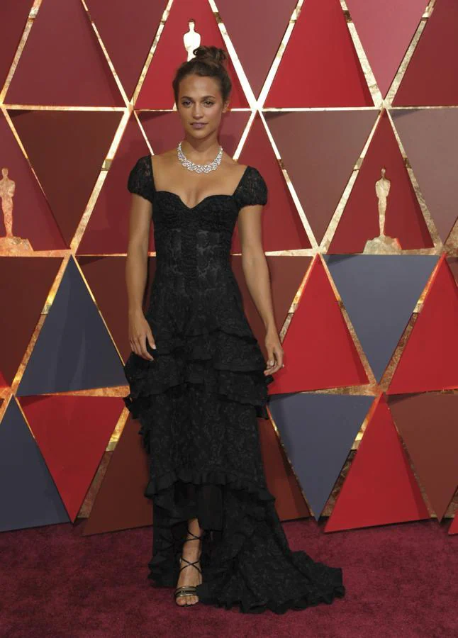 Alicia Vikander en 2017 - Los vestidos más icónicos de los Oscar. Fiel a Louis Vuitton, firma de la que es imagen, lució un modelo negro asimétrico de encaje con tintes flamencos compuesto por varios volantes que se ajustaban a la silueta.