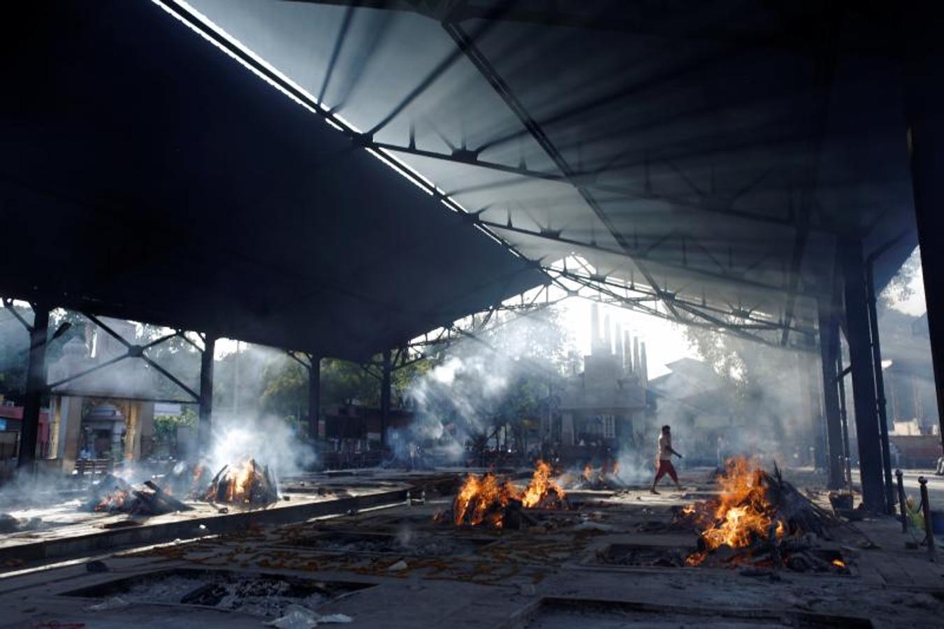 Una persona pasa junto a los incendios funerarios en un crematorio en Nueva Delhi el pasado sábado. 