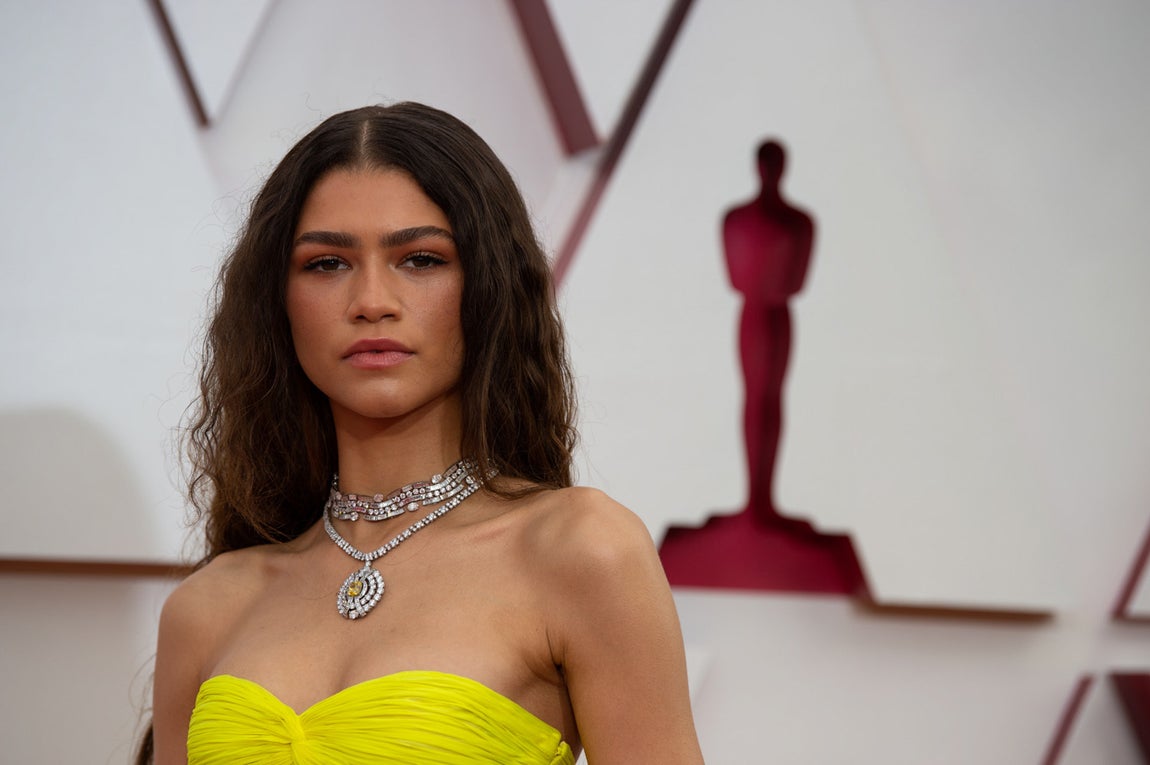 Zendaya en los Oscar 2021. La cantante ha optado por dejar su larga melena suelta, estirando su rizo natural y peinándola con raya en el medio. Con una piel perfecta, Zendaya ha optado por un look ‘no make up’, sacando partido a sus características cejas.
