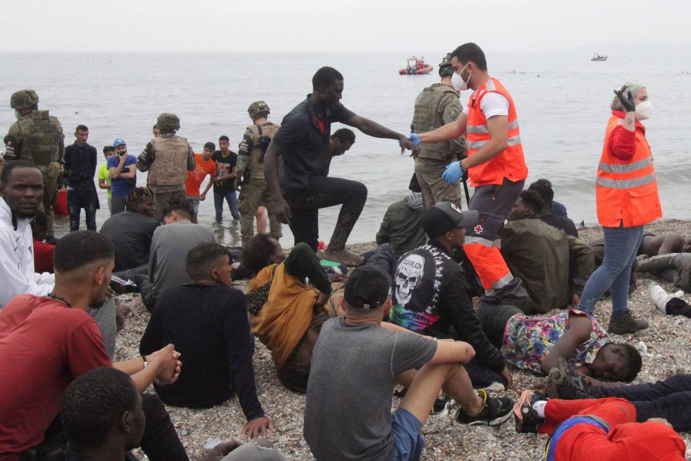 Miembros del Ejército y Cruz Roja ayudan a los inmigrantes que han conseguido cruzar uno de los espigones fronterizos de Ceuta. 
