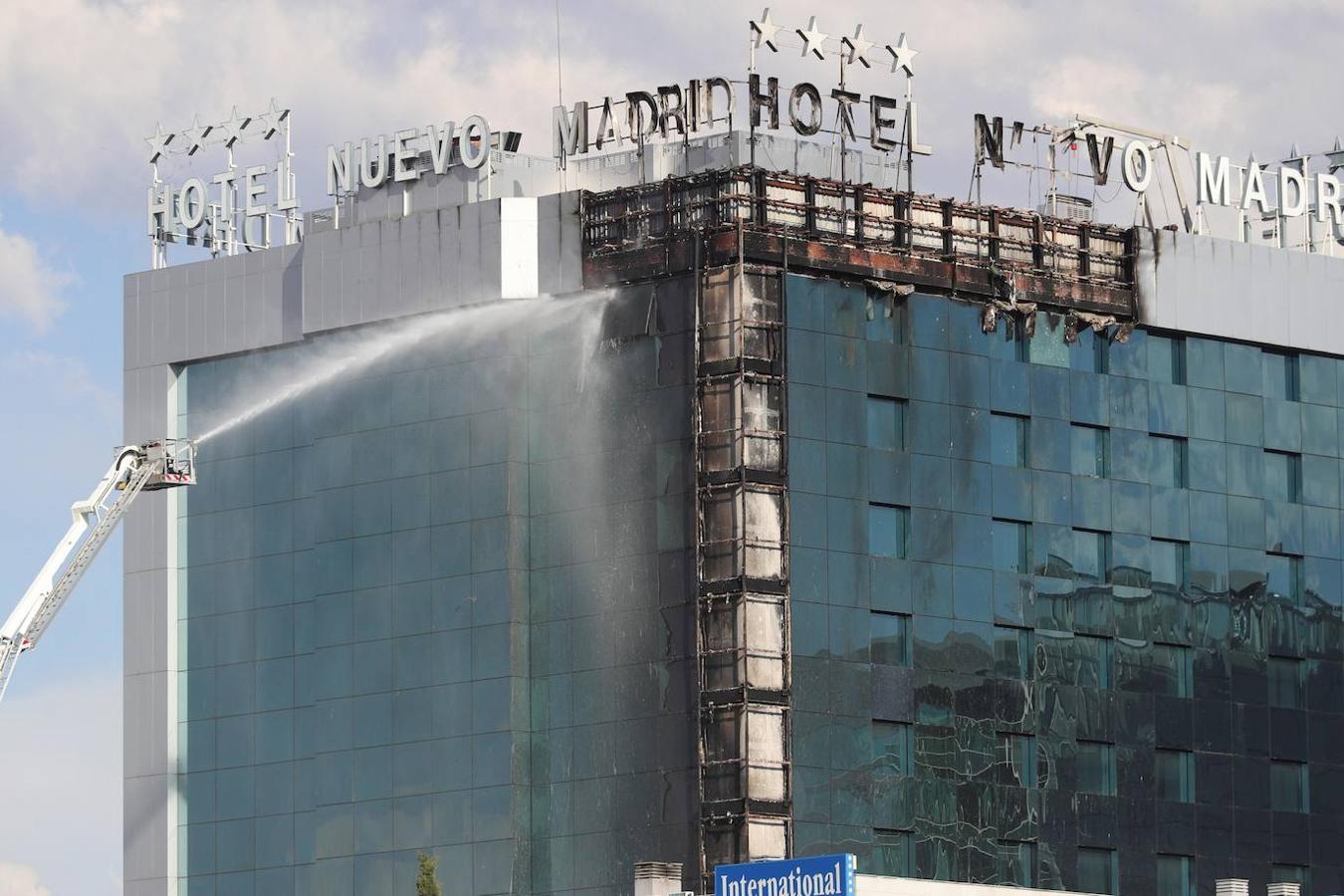 Bomberos extinguen las llamas tras un aparatoso incendio en la fachada exterior del Hotel Nuevo Madrid. 