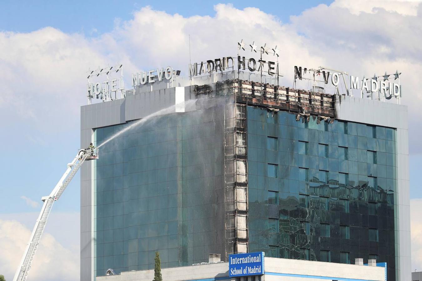 Bomberos extinguen las llamas tras un aparatoso incendio en la fachada exterior del Hotel Nuevo Madrid. 