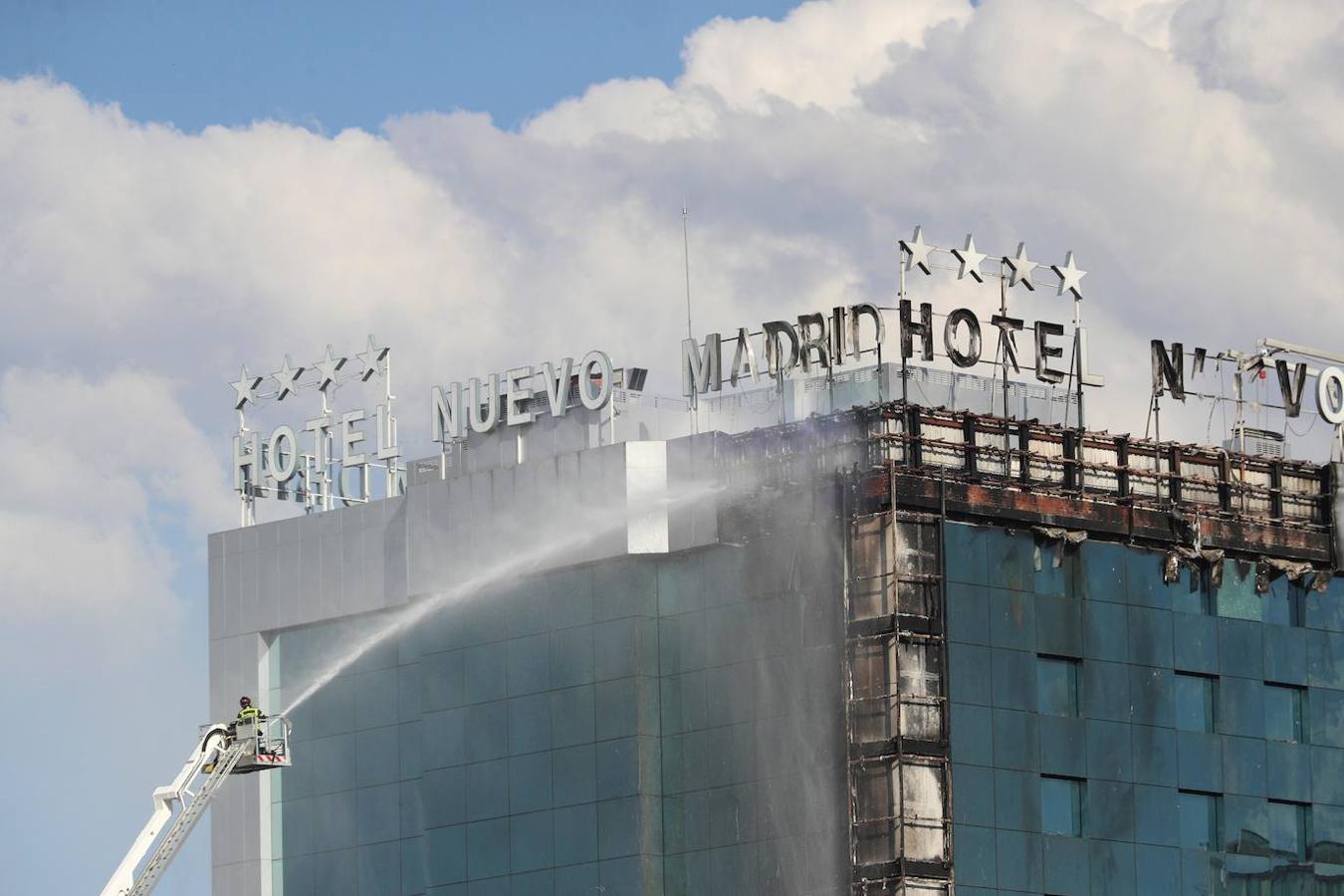 Bomberos extinguen las llamas tras un aparatoso incendio en la fachada exterior del Hotel Nuevo Madrid. 