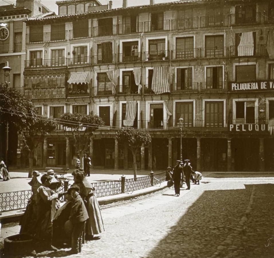 Grupo de personas en la fuente de Zocodover hacia 1904. Al fondo los soportales del Arco de la Sangre. Imagen de un par estereoscópico de la colección de Pedro Pascual Ojesto. Archivo Municipal de Toledo. 