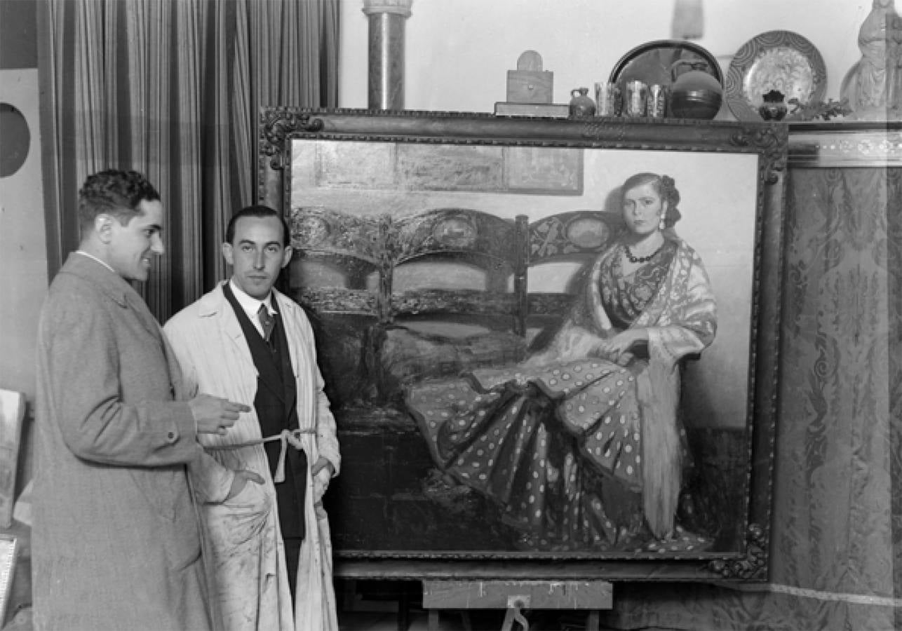 El pintor sevillano José Fernández Venegas posa en su estudio junto al retrato de su sobrina Isabel Gómez y del periodista Manuel Vives en 1933