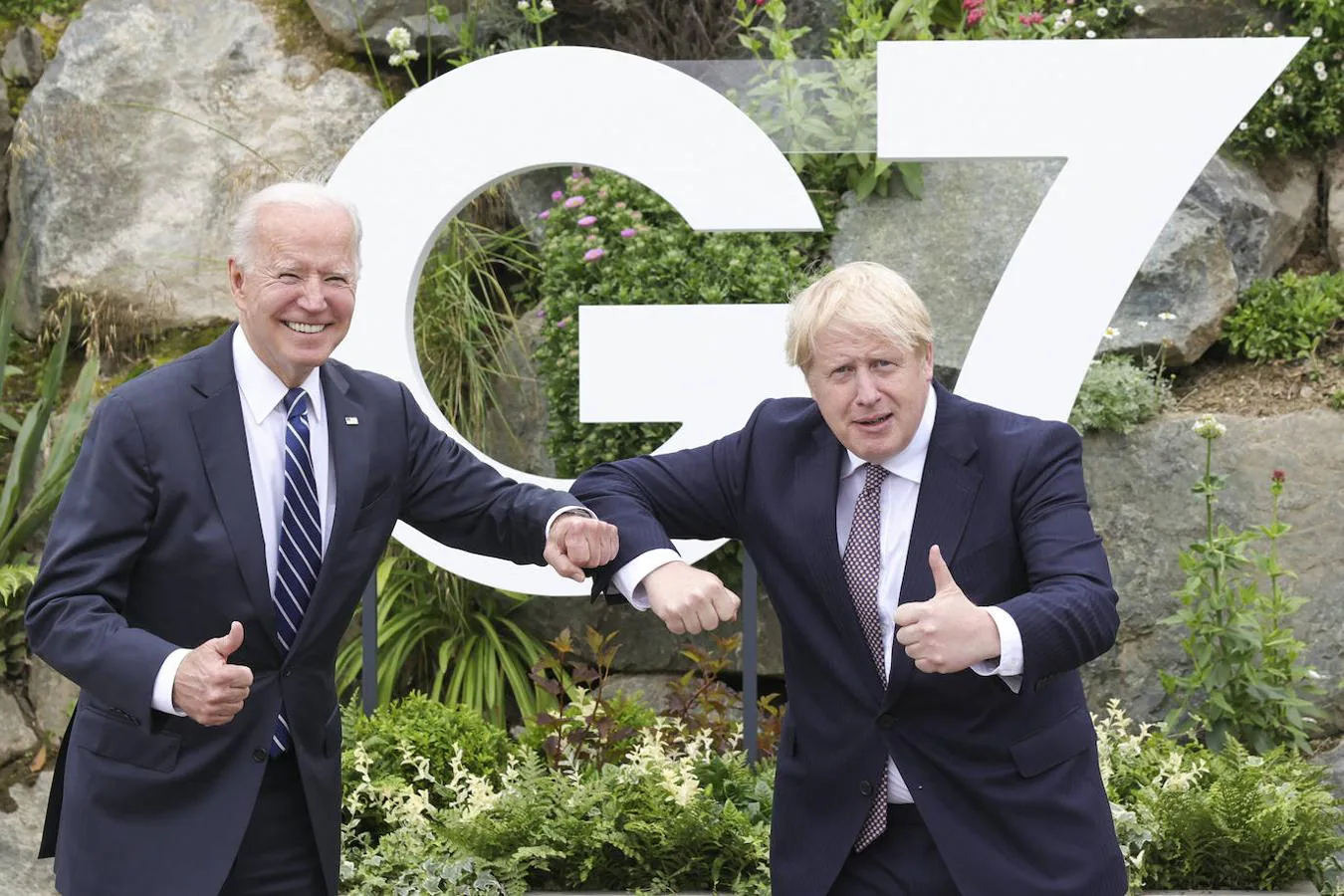 El presidente estadounidense, Joe Biden, y el primer ministro del Reino Unido, Boris Johnson, chocan el codo y levantan el pulgar frente al cartel del G-7. 