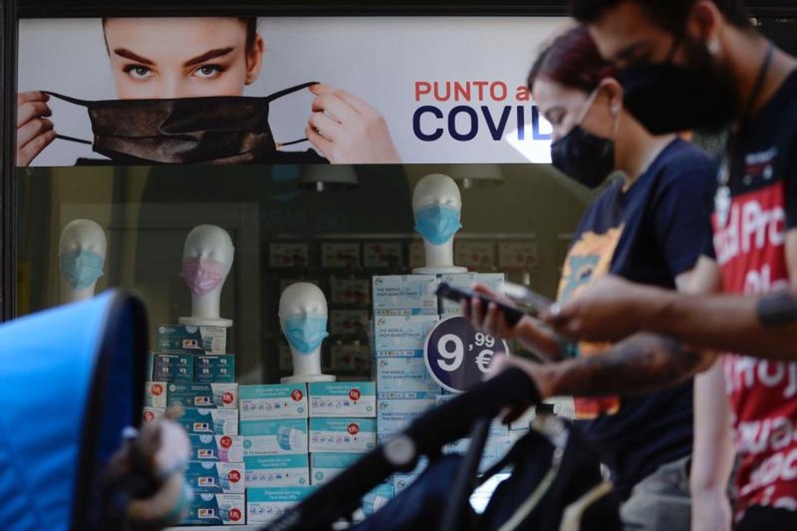 Una pareja pasea con mascarillas por el centro de la ciudad de Valladolid frente a una tienda especializada. 