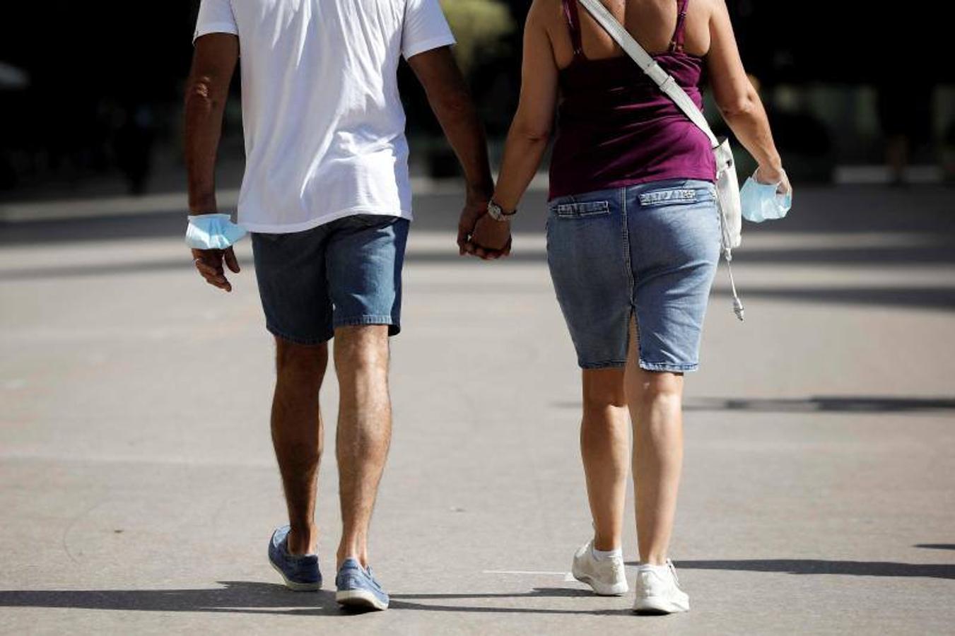 Una pareja pasea con la mascarilla en la mano por el centro de la ciudad de Valladolid. 