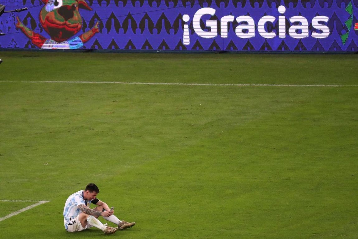 La soledad del campeón. Messi, sentado solo en el césped del estadio de Maracaná, celebra con sus familiares el triunfo en la Copa América a través de una videollamada. Nadie mejor que ellos sabe lo que ha sufrido cuando los éxitos con su país no llegaban.