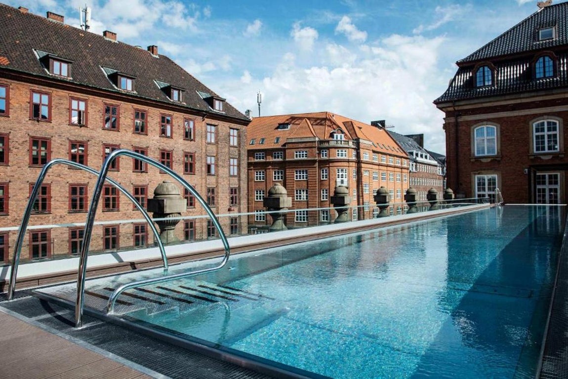 Villa Copenhagen, en Copenhague. Una de las pocas piscinas al aire libre de Copenhague en encuentra en la azotea de Villa Copenhagen. Veinticinco metros de longitud y una temperatura del agua entre 28 y 30ºC convierten a este rincón en un magnífico plan para desconectar y descansar. El agua se calienta de manera sostenible por un sistema que aprovecha el exceso de calor de los sistemas de enfriamiento del hotel. Desde la piscina puede divisarse el Tívoli, el parque de atracciones de la ciudad.