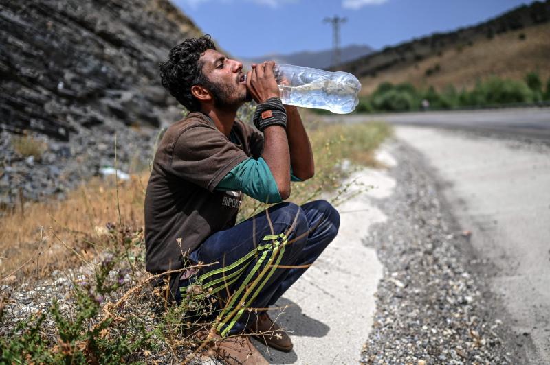 Un emigrante afgano bebe agua mientras descansa en el arcén de una carretera en Tatvan, a orillas del lago de Van, en el este de Turquía. 