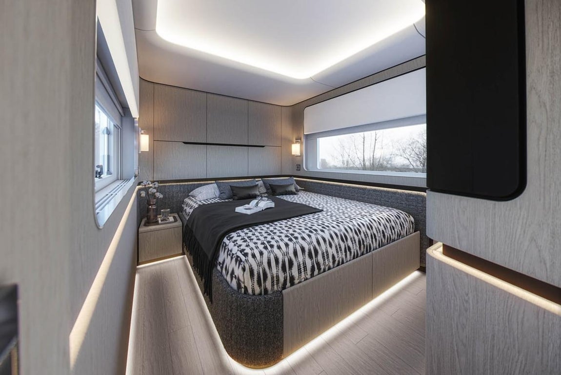 Dembell, la autocaravana inspirada en un yate. El dormitorio principal consta de una cama de 160x200cm y una gran cantidad de armarios. No falta una mesilla de noche, una ventana para poder disfrutar de las vistas y una iluminación muy cuidada.