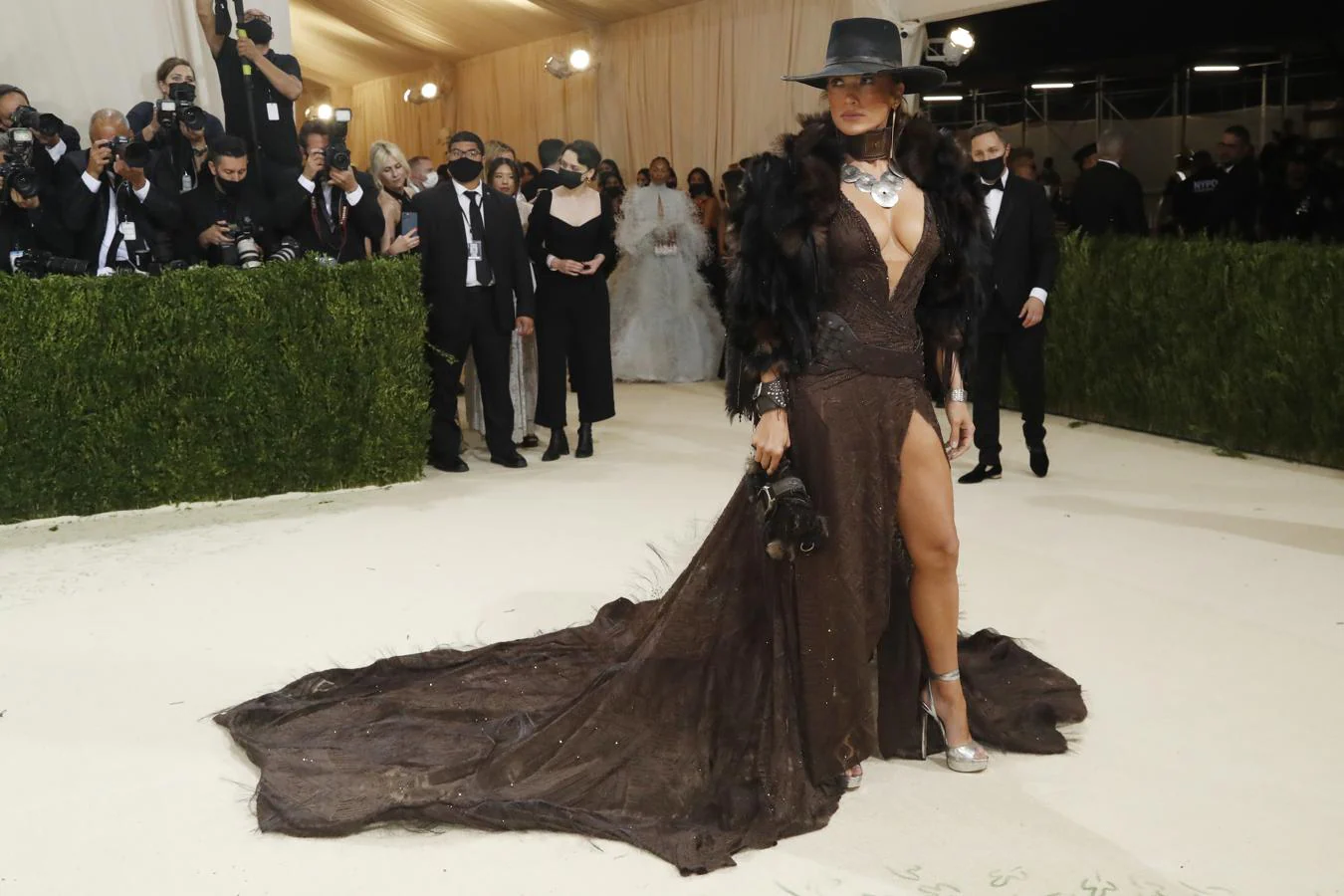 Jennifer Lopez - Alfombra roja de la Gala MET 2021. La artista se inspiró en las 'cowgirls' a la hora de elegir su vestido. Un modelo de Ralph Lauren marrón en el que no faltaban las aberturas y al que añadió un sombrero -muy acorde al look- y una estola.