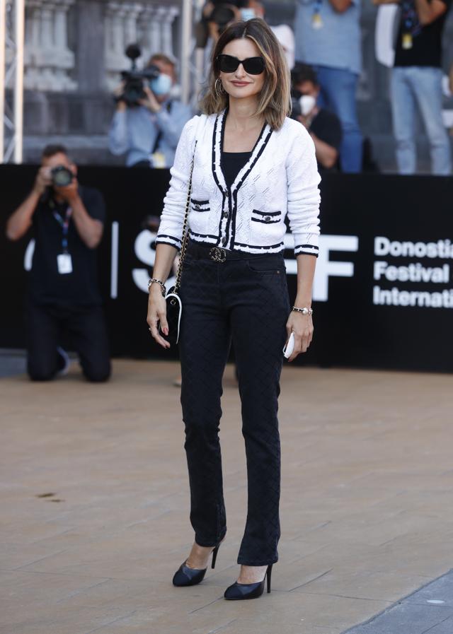 Penélope Cruz recién llegada al festival. Durante el día, apostó por un estilismo más relajado de Chanel, formado por unos jeans negros estampados, rebeca de crochet blanco con bordados negros, cinturón con logo y bolso bicolor.