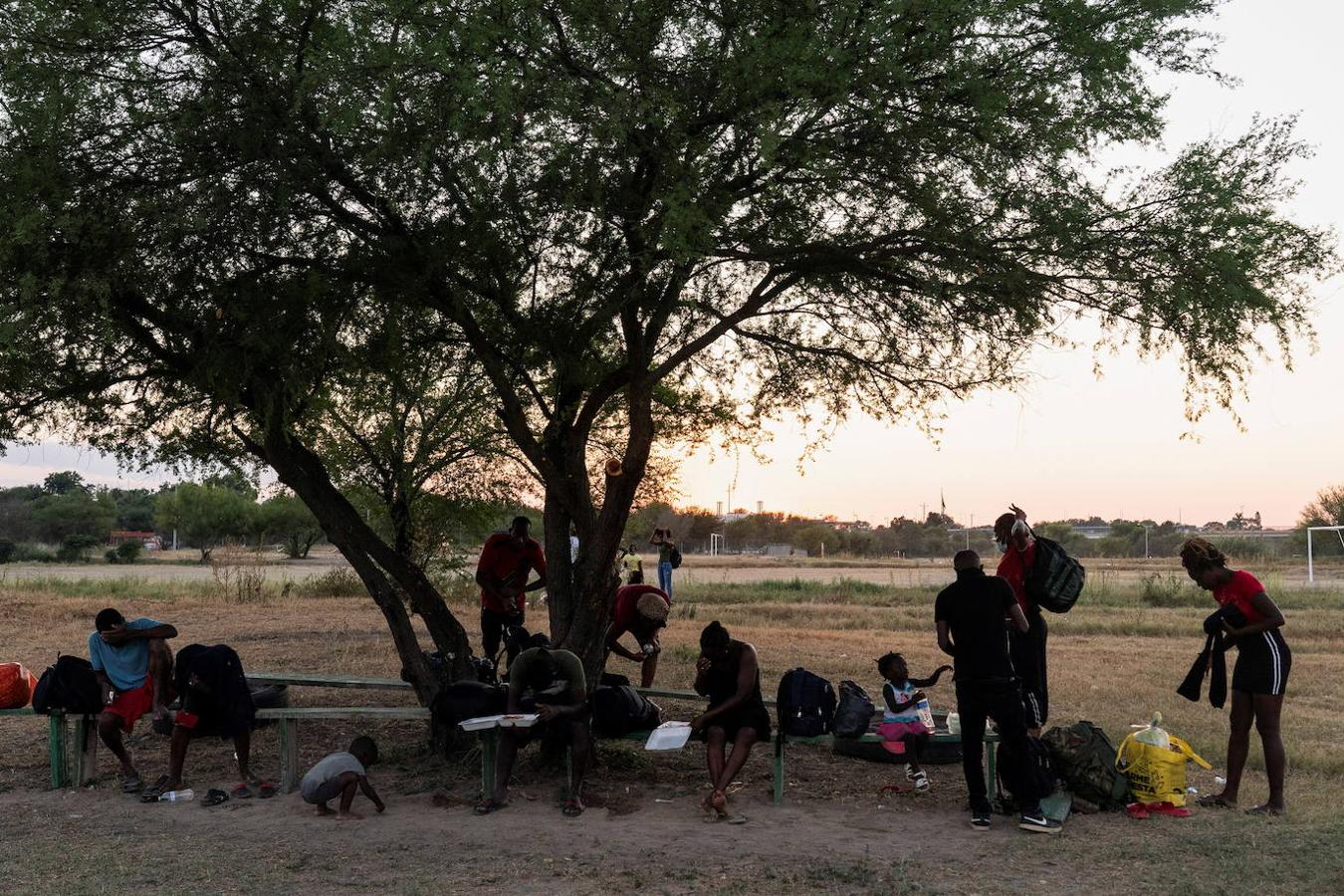 Migrantes solicitantes de asilo descansan en varios bancos después de cruzar el río Grande hacia México. 