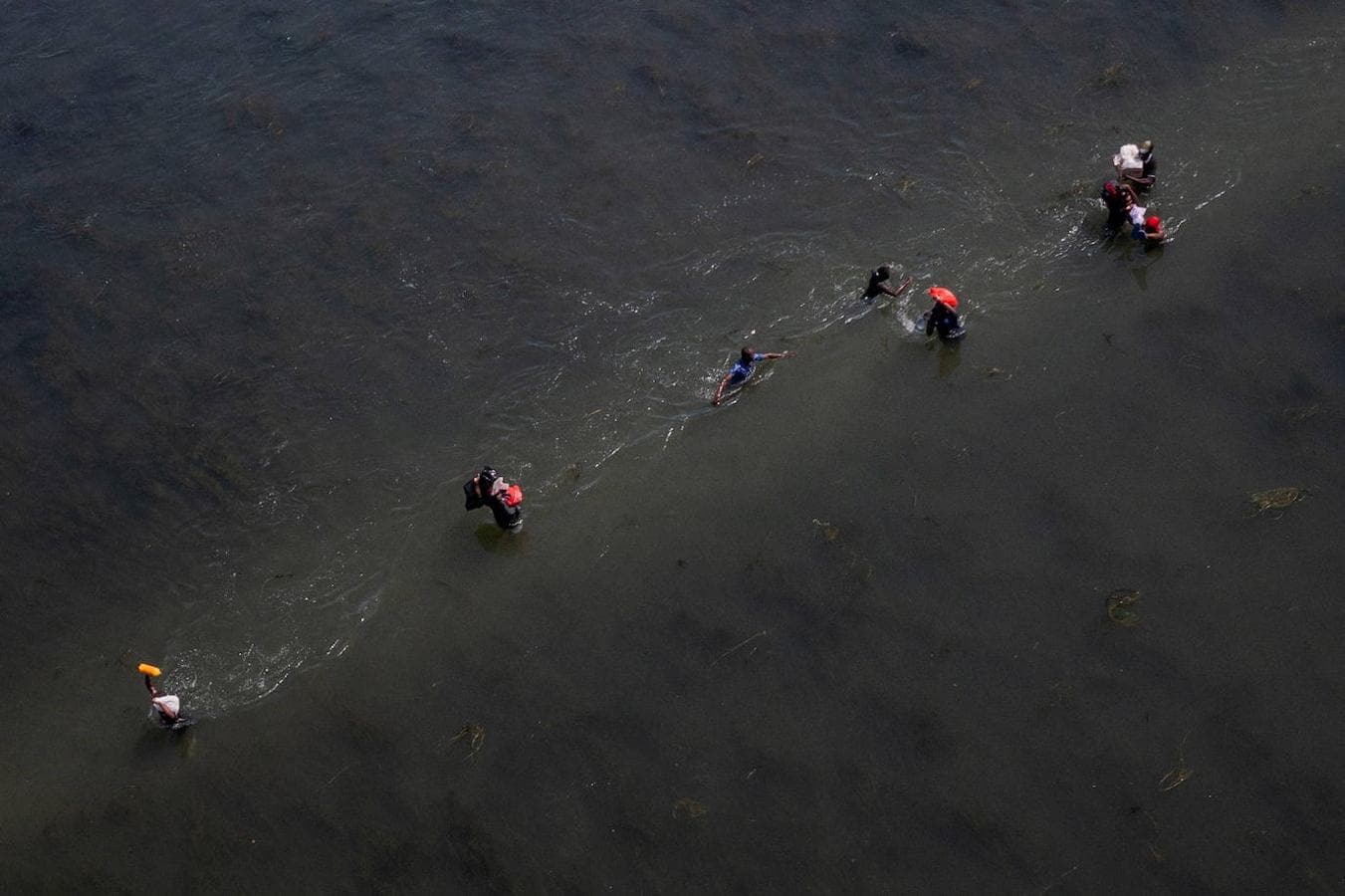 Varios migrantes que buscan refugio en Estados Unidos cruzan el río Bravo de regreso a Acuña, México, mientras otros regresan a los Estados Unidos con suministros. 