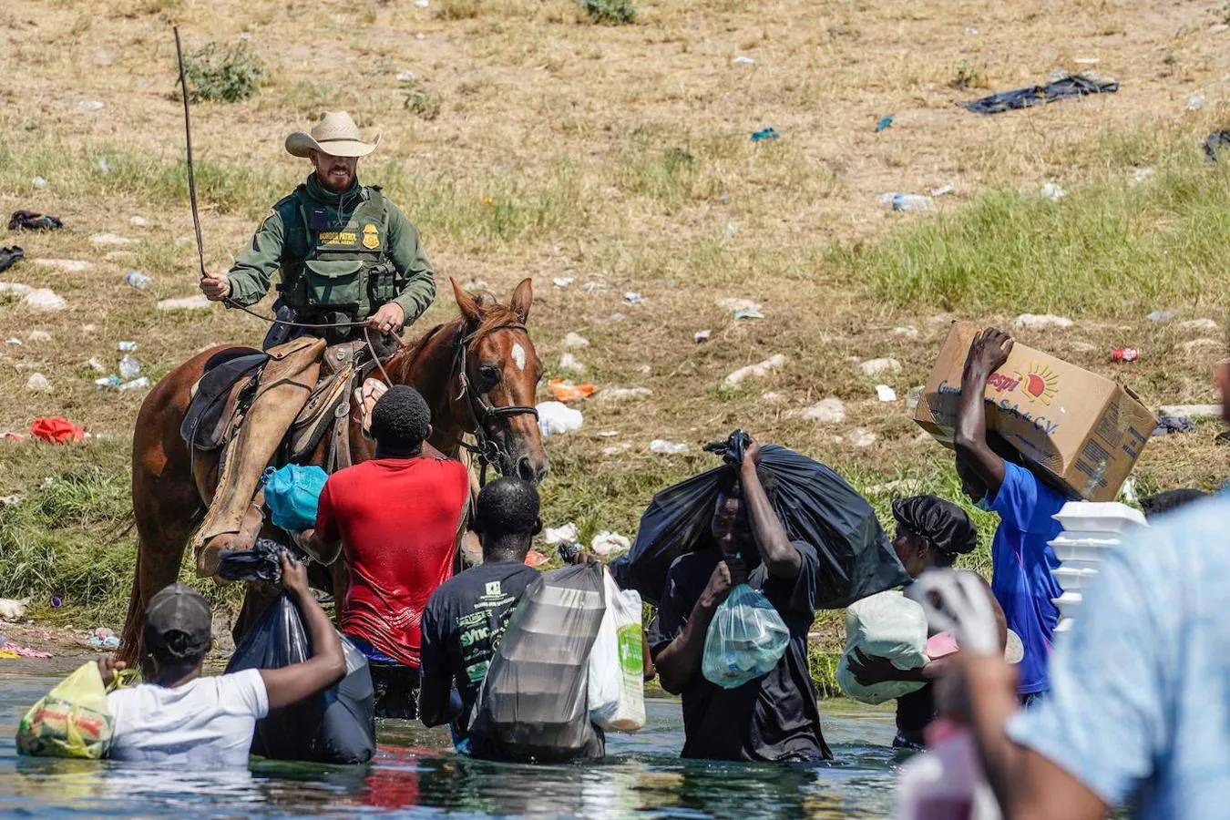 Un agente de la Patrulla Fronteriza de EE.UU. a caballo usa las riendas para evitar que varios migrantes haitianos ingresen a un campamento a orillas del Río Grande. 