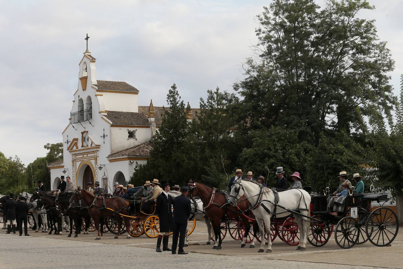 Izado de bandera en Tablada, con los carruajes participantes en el primer paseo por la ciudad.