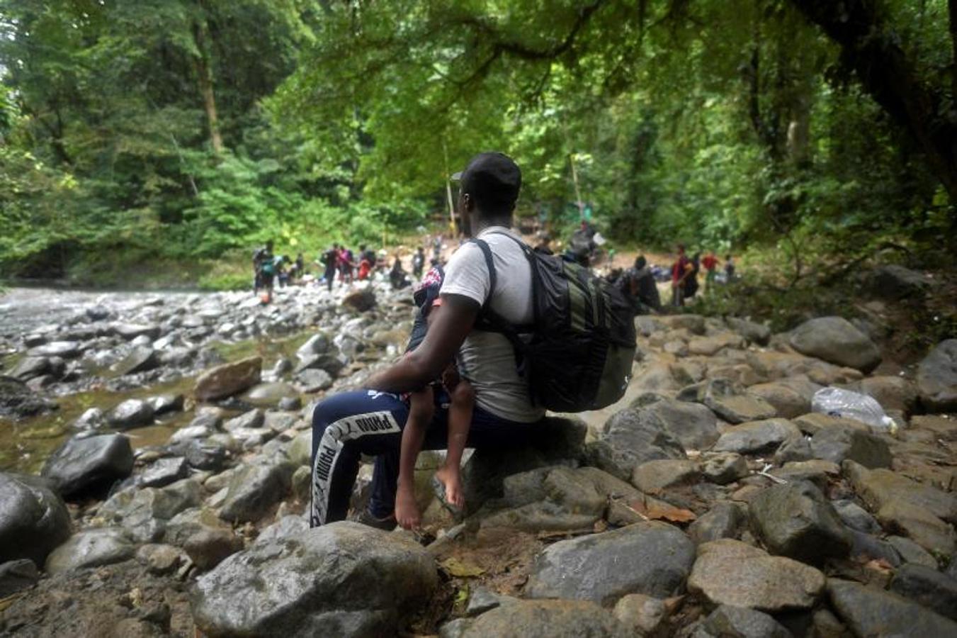 Un haitiano con un niño pequeño descansa mientras cruzan el tapón de Darién. 