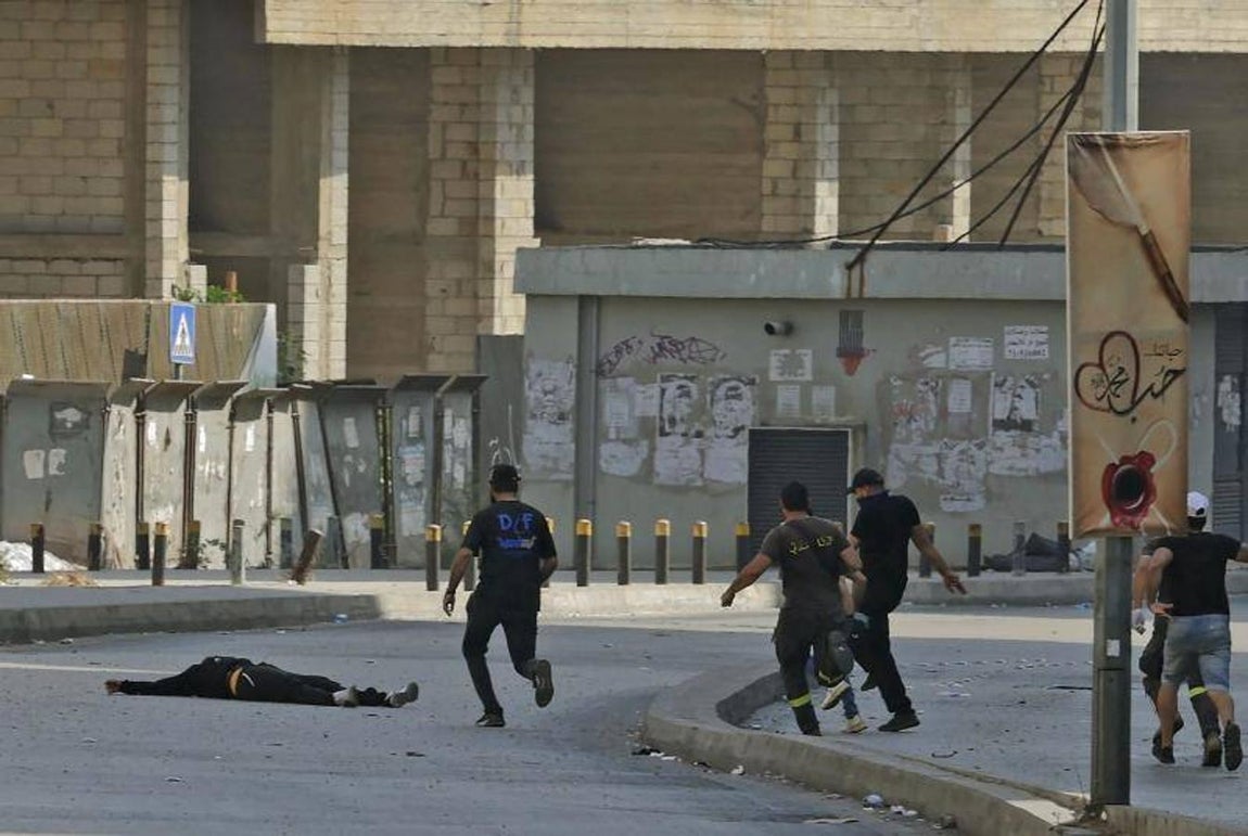 Milicianos chiíes acuden a socorrer a un hombre que yace sobre el asfalto durante los enfrentamientos. 