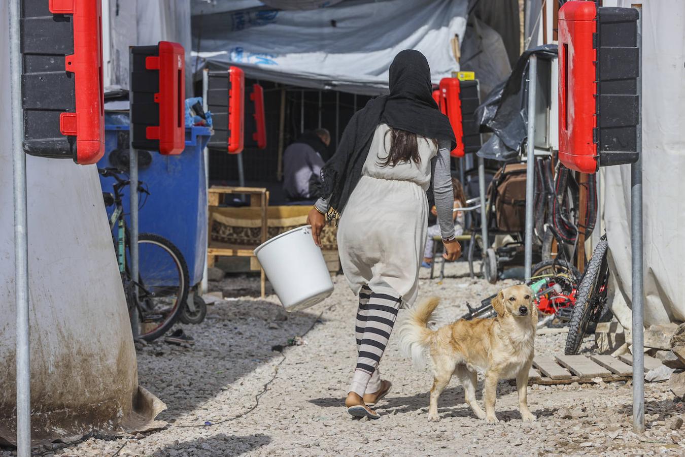 Una mujer porta un cubo cargado con agua por el campo de refugiados. 