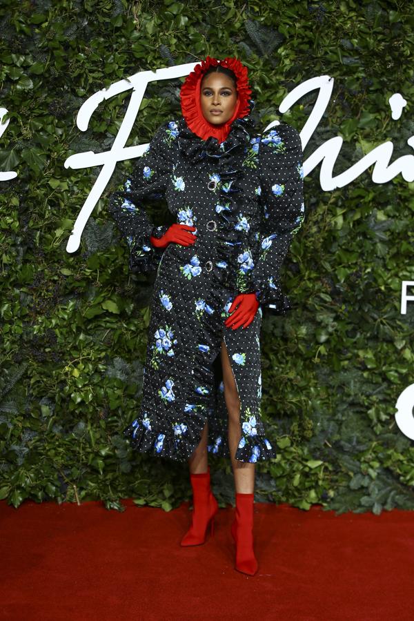 Cindy Bruna - Alfombra roja de los British Fashion Awards. Su estilismo fue uno de los más llamativos de la noche con un vestido midi con topos y flores que poseía mangas farol XXL, volantes en el bajo y una capucha roja a juego con los botines.