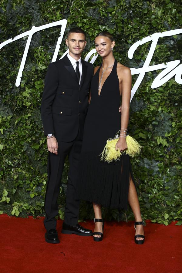 Romeo Beckham y Mia Regan - Alfombra roja de los British Fashion Awards. El benjamín de la familia Beckham acudió junto a su novia Mia Regan, quien eligió un minimalista diseño negro con escote palabra de honor de Proenza Schouler.