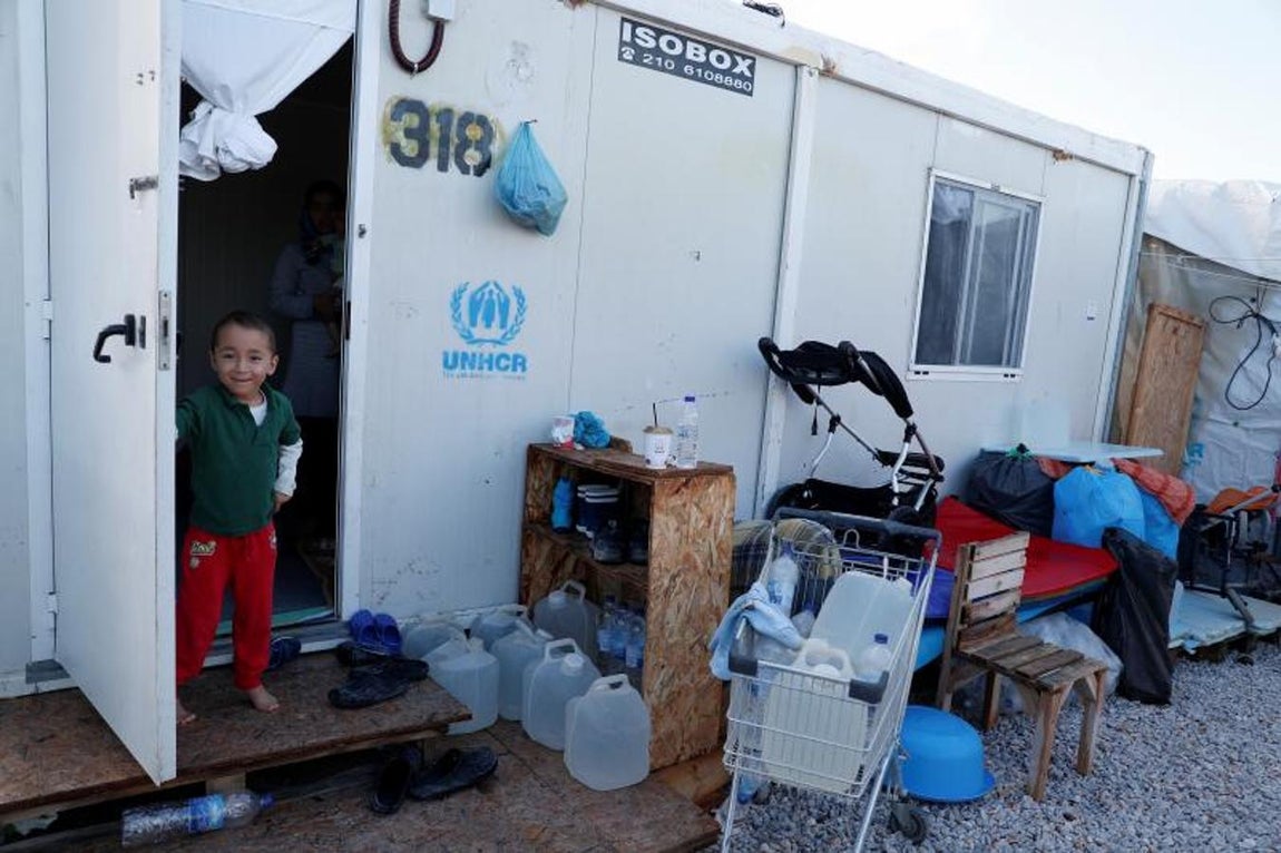 Un menor, descalzo, con garrafas de agua y enseres de su precaria casa. 