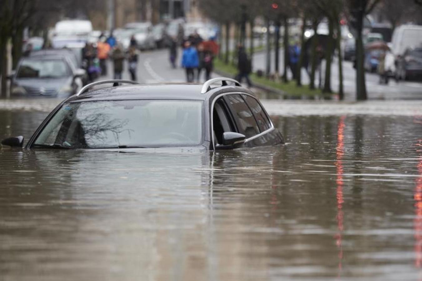 Un vehículo cubierto de agua en una vía inundada del barrio de Rotxapea. 