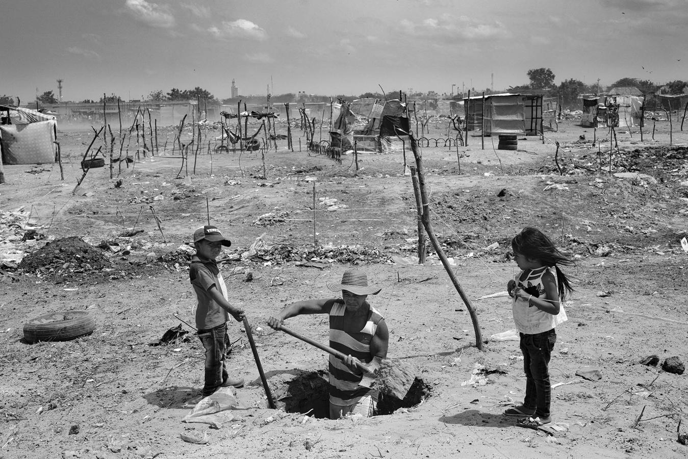 José Luis Rincón y dos de sus hijos construyen una fosa séptica en abril de 2021 en el terreno que han invadido para su familia en un asentamiento de Colombia. 