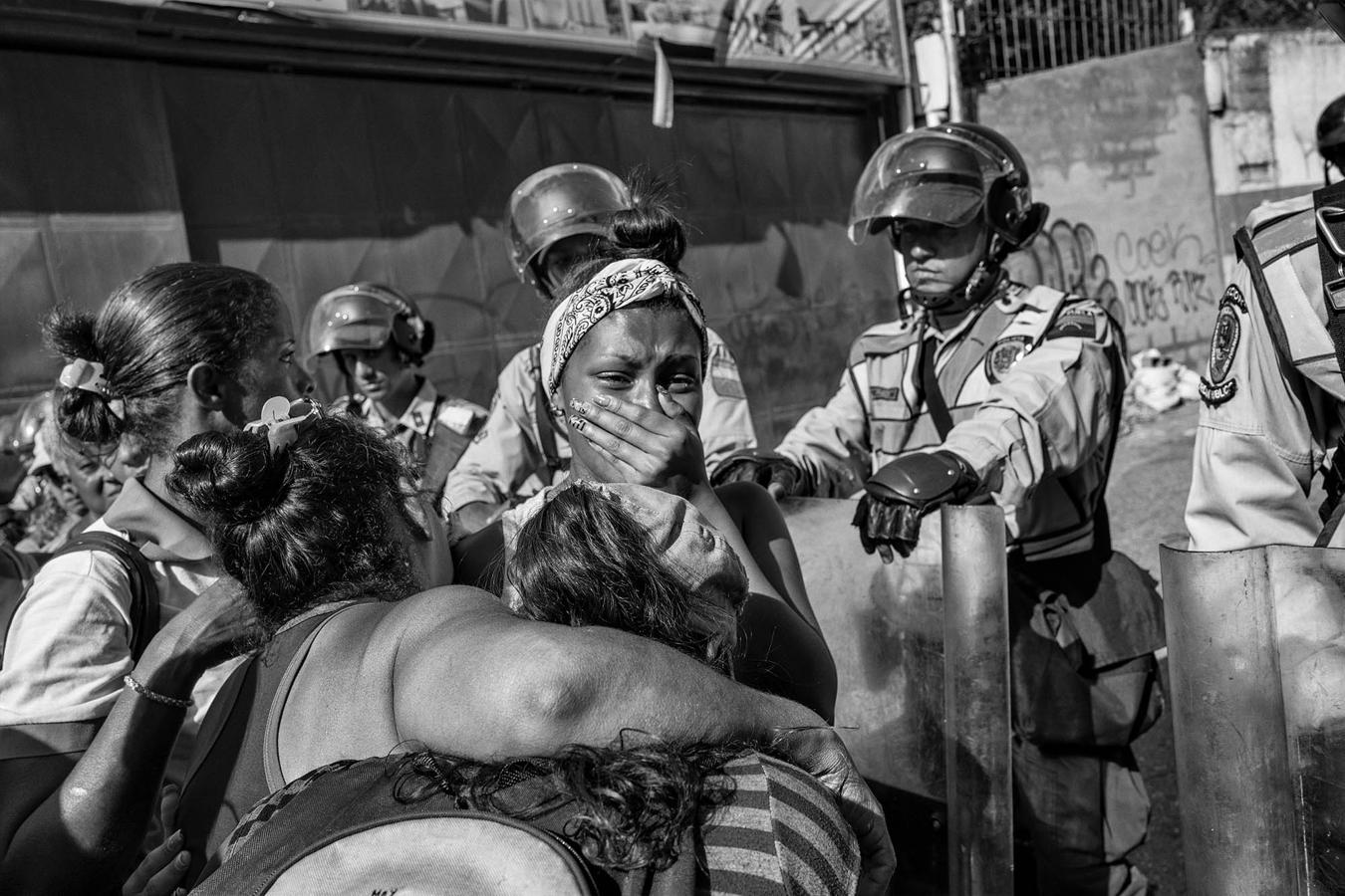 Una mujer llora frente a la policía chavista por la angustia de no saber de su hermano, que es uno de los 600 detenidos que se ha amotinado dentro de la comisaría. 