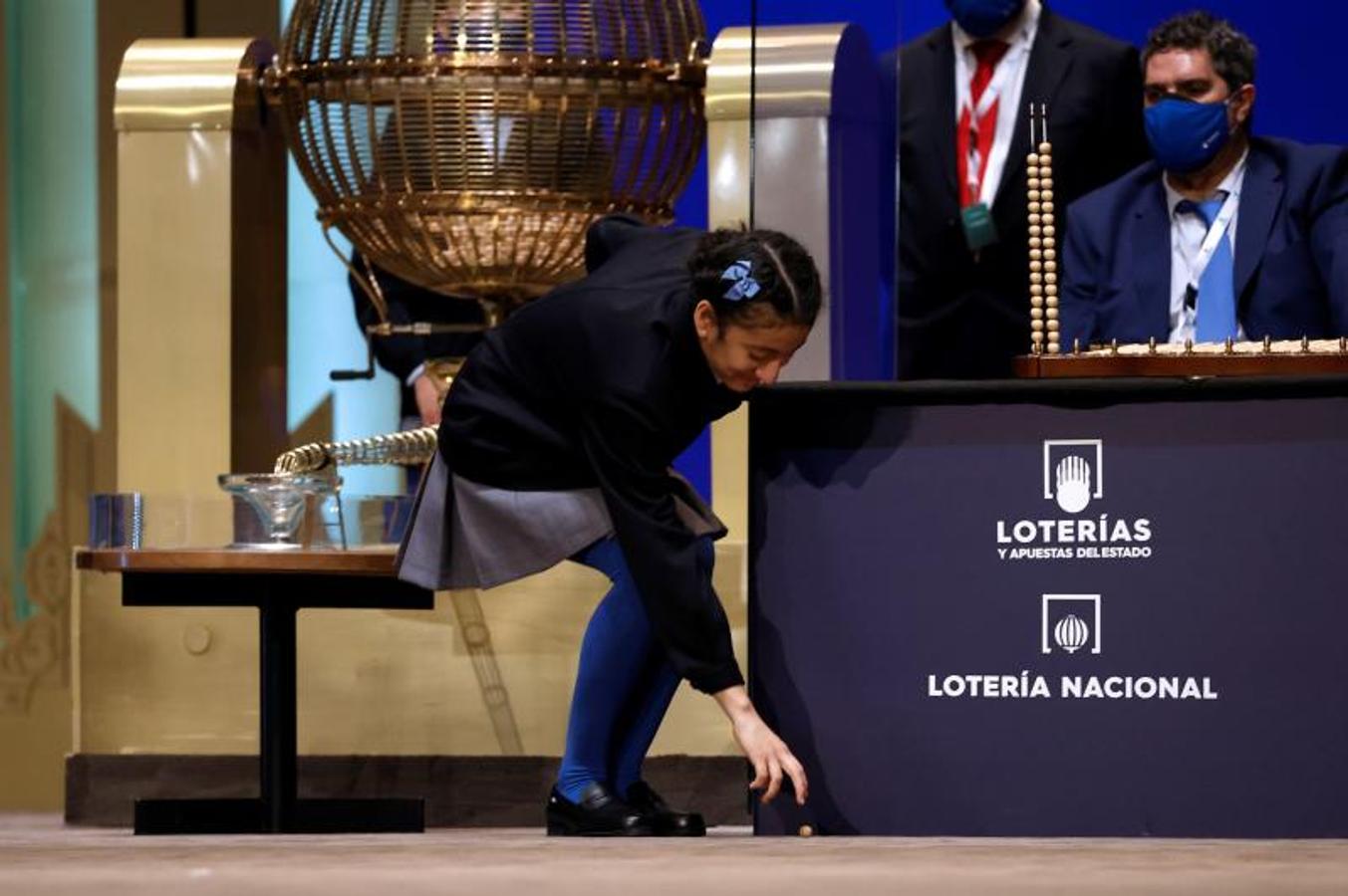 Una niña del Colegio de San Ildefonso recoge la bola del primer premio al 86148 del sorteo de la Lotería de Navidad celebrado en el Teatro Real de Madrid este miércoles. 