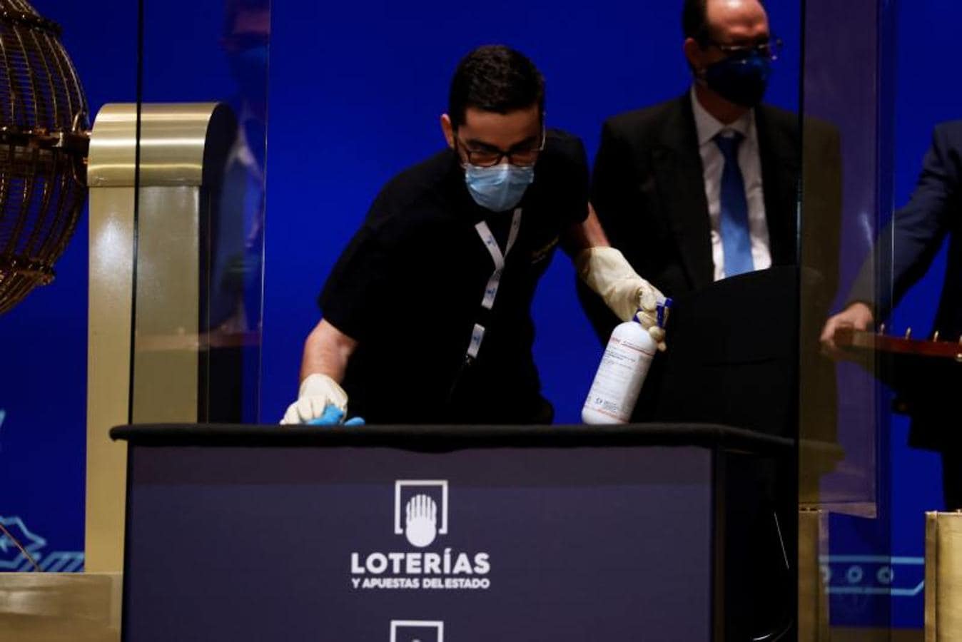 Entre tabla y tabla un operario desinfecta el mobiliario del sorteo de la Lotería de Navidad celebrado en el Teatro Real de Madrid este miércoles. 