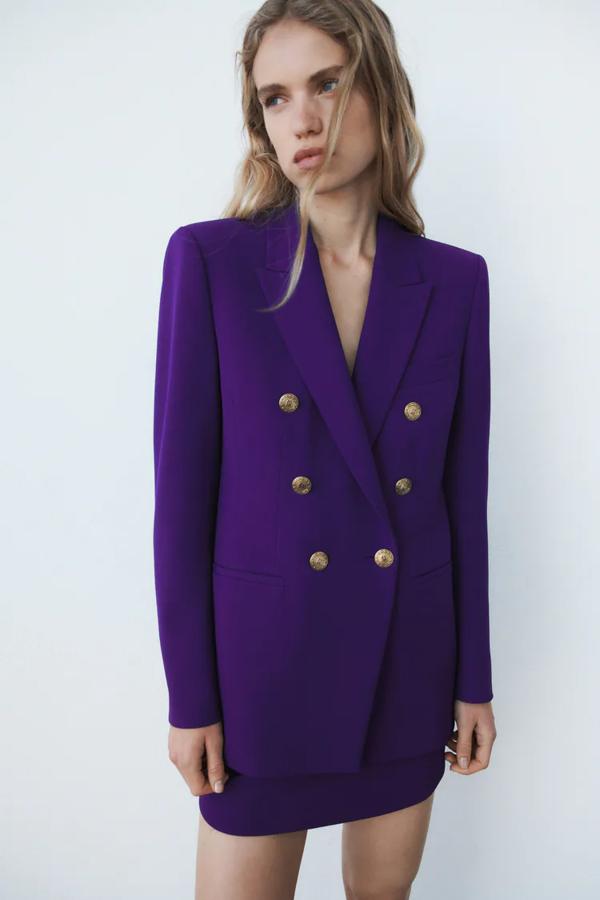 Con botones dorados. Blazer entallada con cuello solapa y cierre cruzado con botones dorados, en color morado de Zara. Precio: 49,99€ /antes: 79,95€